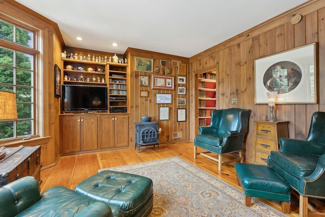 living room featuring light wood-type flooring, a healthy amount of sunlight, and wooden walls