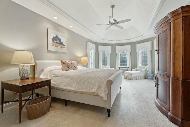 carpeted bedroom with a raised ceiling, ceiling fan, and ornamental molding