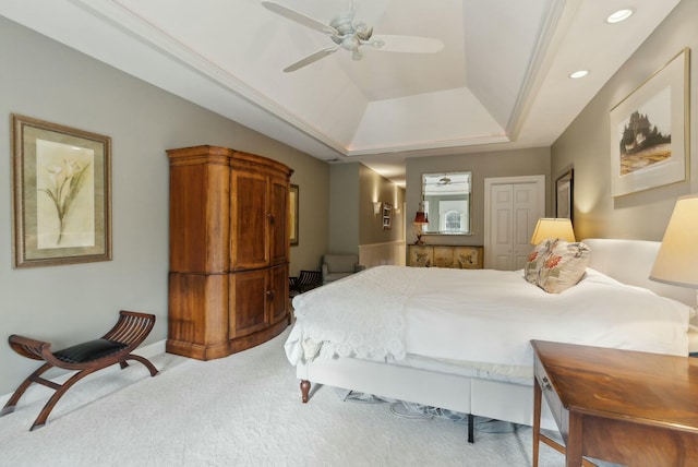 carpeted bedroom featuring ceiling fan, a closet, and a tray ceiling