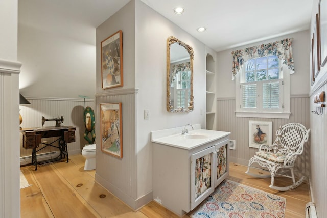 bathroom featuring a baseboard heating unit, toilet, wood-type flooring, and built in shelves