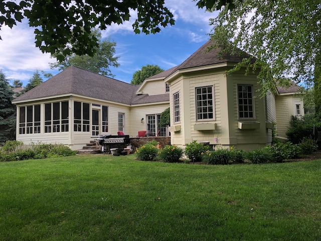 rear view of house featuring a sunroom and a lawn