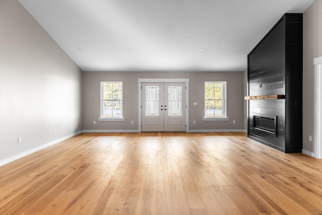 unfurnished living room with a large fireplace, light hardwood / wood-style flooring, a wealth of natural light, and vaulted ceiling