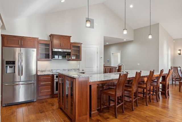 kitchen featuring appliances with stainless steel finishes, high vaulted ceiling, hanging light fixtures, and a spacious island