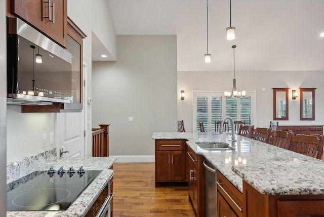 kitchen featuring an inviting chandelier, a center island with sink, sink, appliances with stainless steel finishes, and light hardwood / wood-style floors