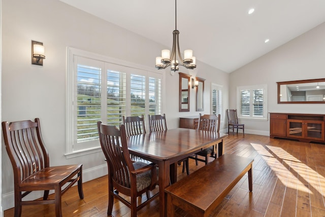 dining area featuring hardwood / wood-style flooring, a notable chandelier, and vaulted ceiling