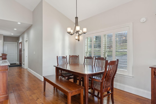 dining space with a notable chandelier, plenty of natural light, wood-type flooring, and lofted ceiling