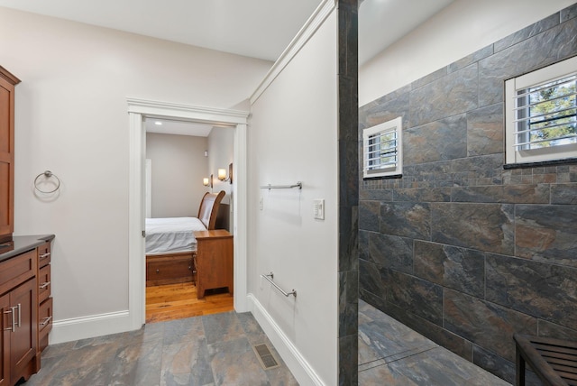 bathroom with a tile shower and vanity