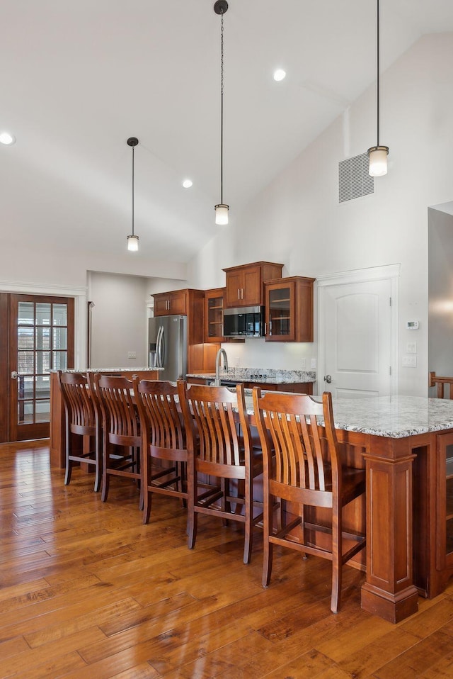 kitchen with light stone countertops, decorative backsplash, pendant lighting, and stainless steel appliances