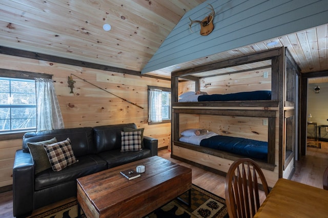 bedroom with multiple windows, wood walls, wood-type flooring, and lofted ceiling