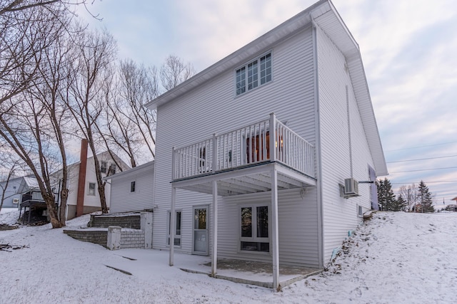 snow covered house featuring a balcony