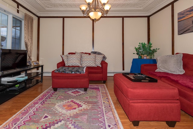 living room featuring wood-type flooring, an inviting chandelier, and ornamental molding