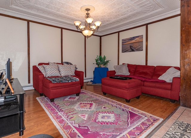 living room with hardwood / wood-style floors, an inviting chandelier, baseboard heating, and crown molding