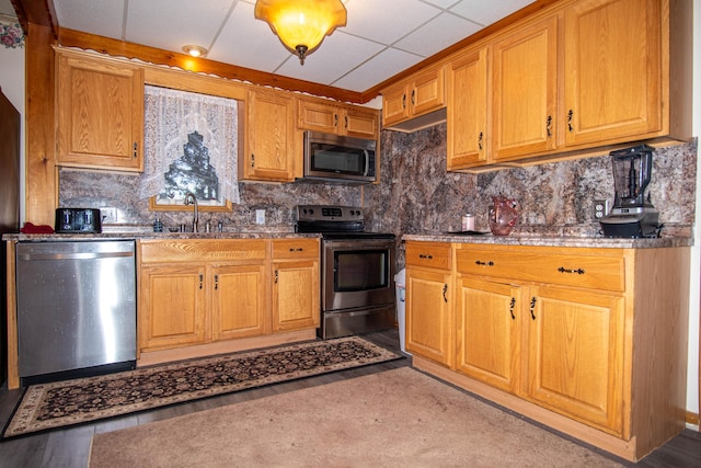 kitchen featuring backsplash, a drop ceiling, sink, and stainless steel appliances