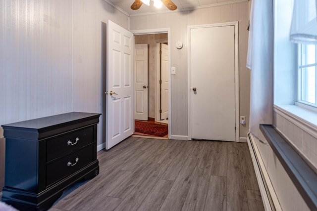 unfurnished bedroom with hardwood / wood-style floors, ceiling fan, ornamental molding, and baseboard heating