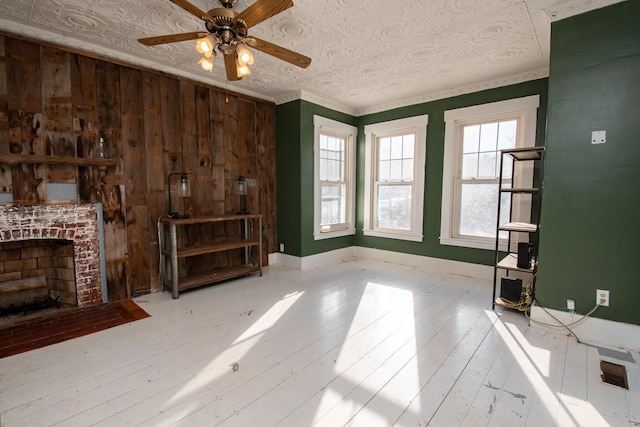 1153 Dexter Rd, Dover-Foxcroft, ME 04426 - unfurnished living room featuring ceiling fan, a fireplace, an ornate ceiling, wood walls, and hardwood / wood-style flooring