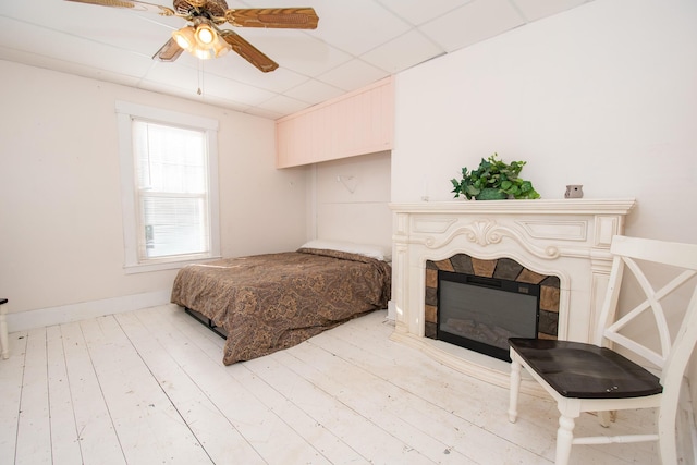 1153 Dexter Rd, Dover-Foxcroft, ME 04426 - bedroom featuring a glass covered fireplace, a ceiling fan, and light wood-type flooring