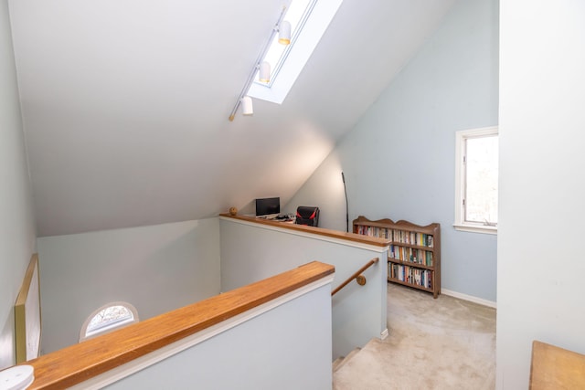 corridor with light carpet and vaulted ceiling with skylight