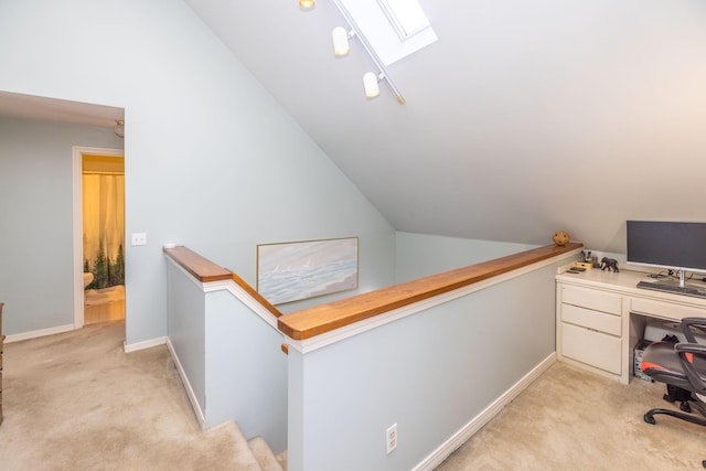 carpeted office space featuring vaulted ceiling with skylight