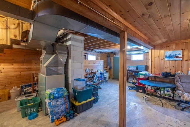 basement featuring heating unit, wood ceiling, and wood walls