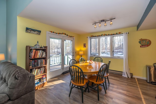 dining room featuring wood-type flooring, a baseboard radiator, and track lighting