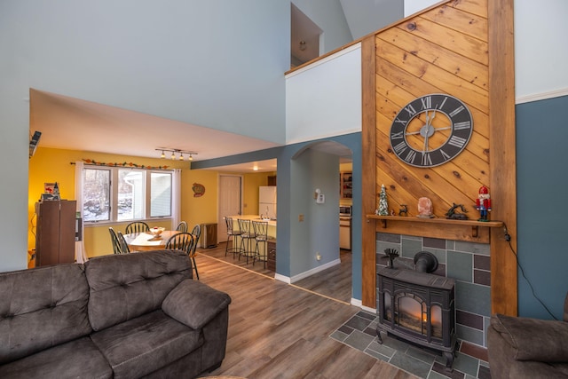 living room featuring a wood stove, high vaulted ceiling, and dark hardwood / wood-style floors