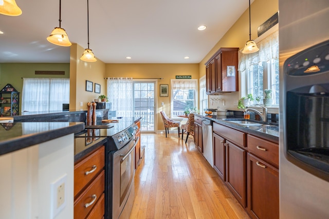 kitchen with appliances with stainless steel finishes, pendant lighting, light wood-type flooring, and sink