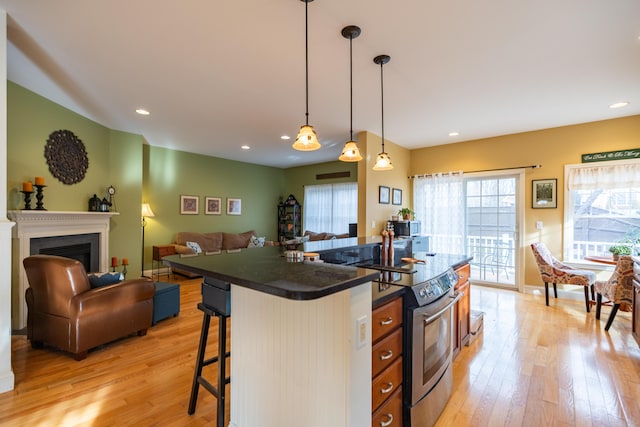 kitchen featuring a center island, decorative light fixtures, light wood-type flooring, stainless steel electric range oven, and a kitchen breakfast bar