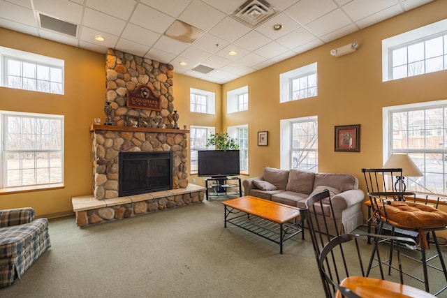 carpeted living room featuring a towering ceiling, a fireplace, and a drop ceiling