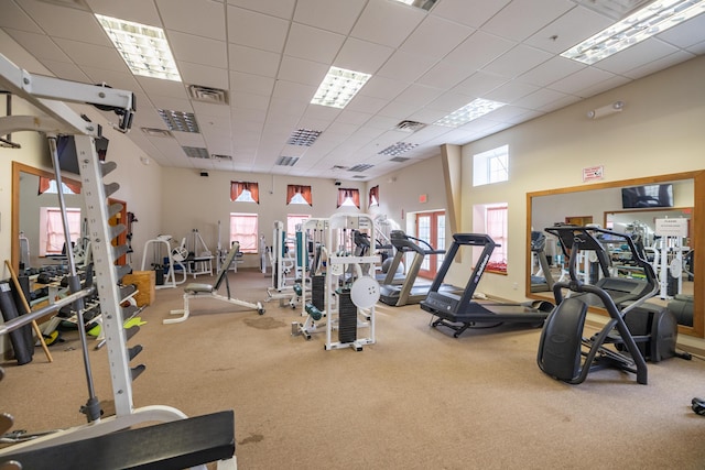 exercise room featuring a towering ceiling, a paneled ceiling, and carpet