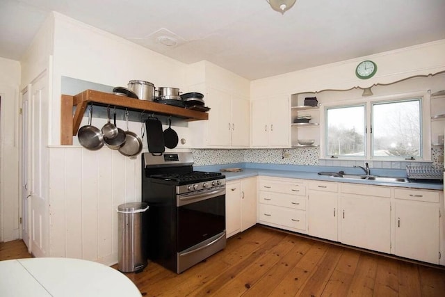 kitchen featuring gas range, sink, dark wood-type flooring, decorative backsplash, and white cabinets