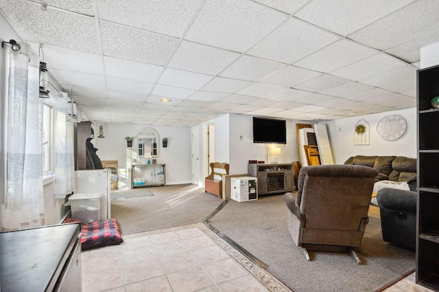 carpeted living area featuring a drop ceiling and tile patterned floors