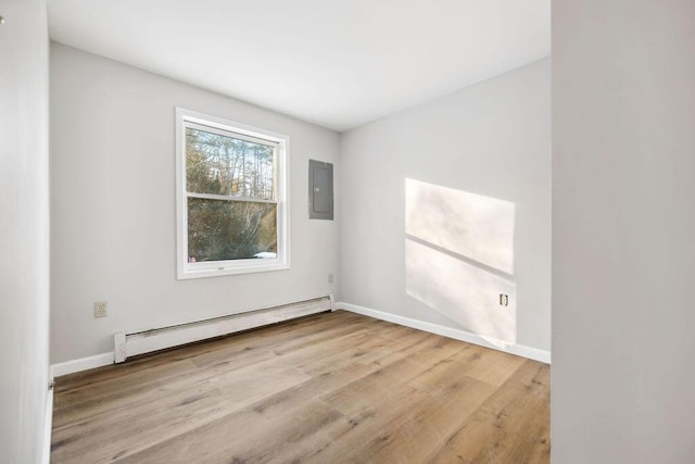 empty room featuring a baseboard heating unit, light wood-type flooring, electric panel, and baseboards