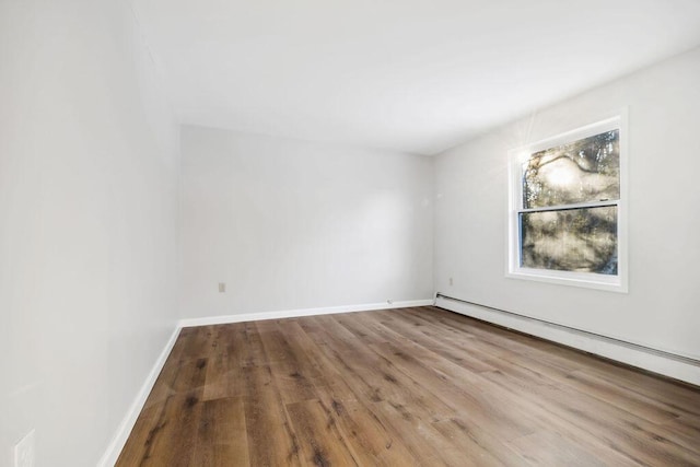 empty room with baseboards, baseboard heating, and wood finished floors