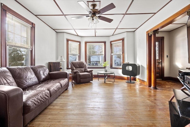 living room with light wood-type flooring, ceiling fan, and a healthy amount of sunlight