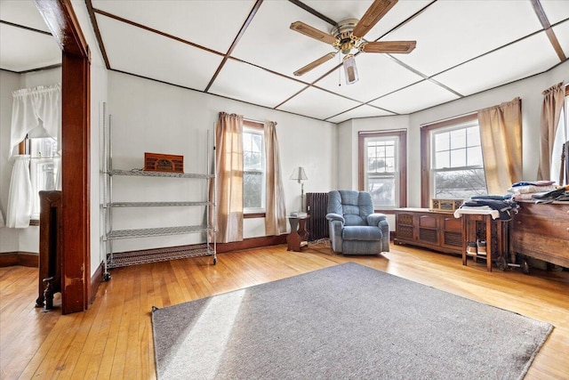 living area featuring ceiling fan, hardwood / wood-style floors, and a drop ceiling