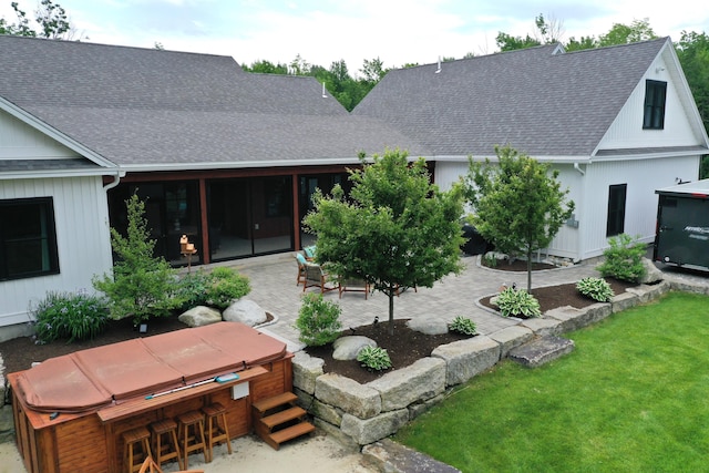 back of property featuring a bar, a patio area, a yard, and a hot tub