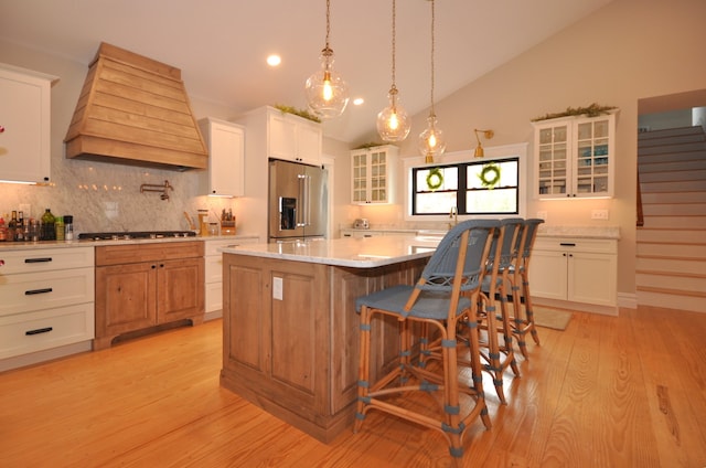 kitchen featuring white cabinets, premium range hood, a kitchen island, and high quality fridge