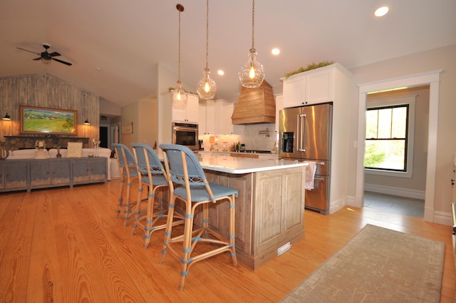 kitchen with premium range hood, stainless steel appliances, decorative light fixtures, white cabinetry, and a large island