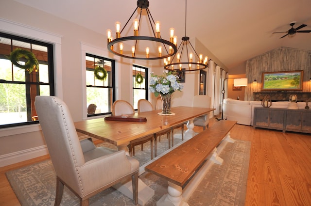 dining space featuring a wall unit AC, lofted ceiling, light hardwood / wood-style floors, and ceiling fan with notable chandelier