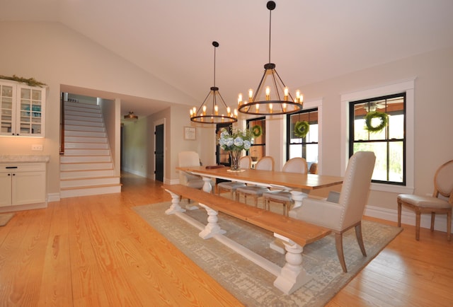 dining area featuring light wood-type flooring, lofted ceiling, and an inviting chandelier