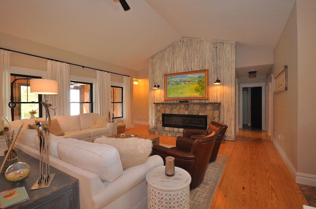 living room with a fireplace, vaulted ceiling, and light hardwood / wood-style flooring