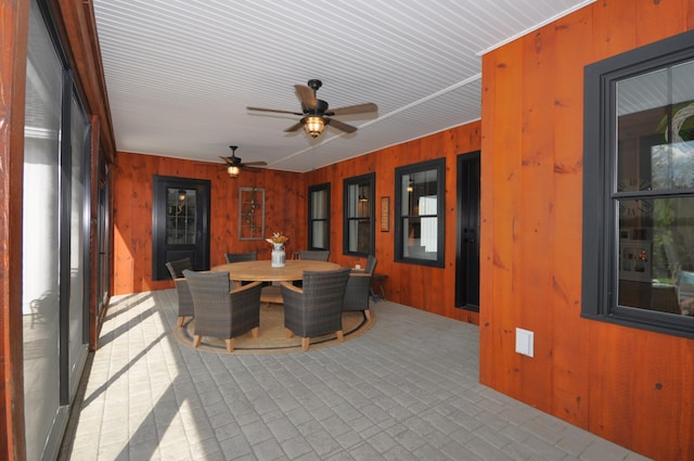 interior space featuring ceiling fan and wooden walls