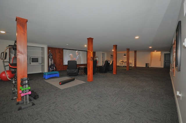 exercise room featuring dark colored carpet and wood walls