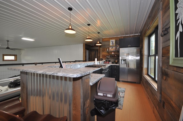 kitchen with pendant lighting, stainless steel fridge, light hardwood / wood-style floors, light stone counters, and a breakfast bar area