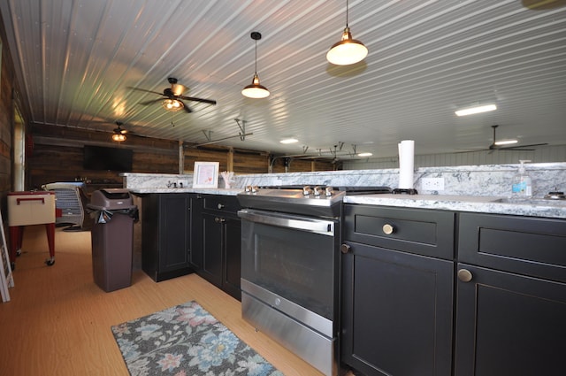 kitchen with light wood-type flooring, light stone counters, sink, hanging light fixtures, and stainless steel range with electric cooktop