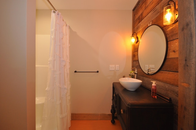 bathroom featuring curtained shower, wooden walls, and vanity