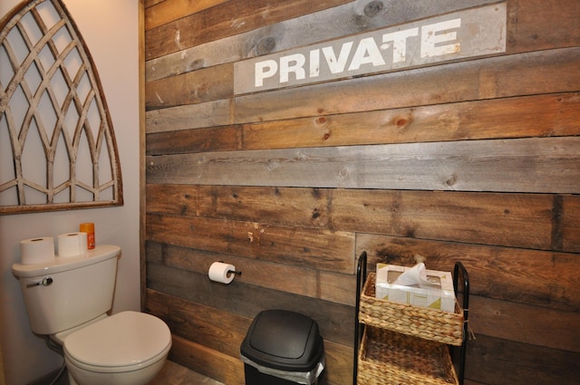 bathroom with toilet and wooden walls