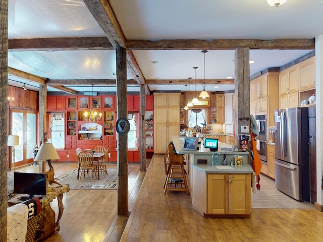 kitchen with sink, appliances with stainless steel finishes, hanging light fixtures, beamed ceiling, and light wood-type flooring