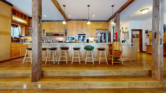 kitchen with light hardwood / wood-style floors, hanging light fixtures, stainless steel appliances, and a kitchen breakfast bar