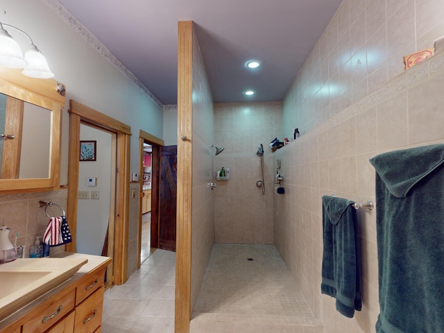 bathroom featuring crown molding, tile walls, vanity, a tile shower, and tile patterned floors